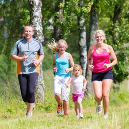 Familie mit 2 Kindern läuft zusammen in der Natur
