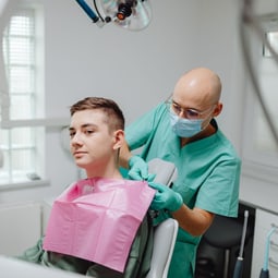 Zahnarzt in einer modernen Klinik bereitet einen jugendlichen Patienten auf eine zahnärztliche Untersuchung vor.