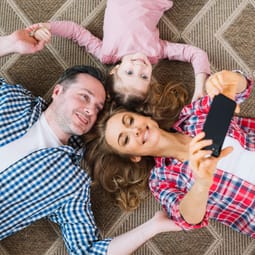 Familie leigend am Boden macht ein Selfie.