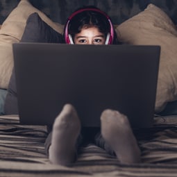 Kleines Kind mit Kopfhörer vor dem Computer.