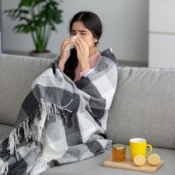 Junge Frau mit Schnupfen auf dem Sofa