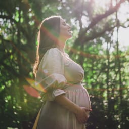Schwangere Frau in einem sonnenbeschienenen Wald
