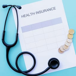 Stethoskop, Krankenversicherungsformular und Eurogeldmünzen