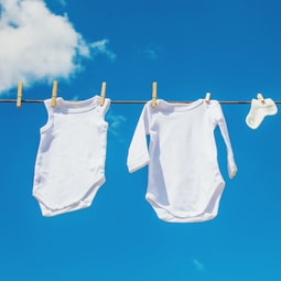 Weisse Babykleidung trocknet an der Sonne draussen.