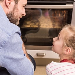 Vater und Tochter schauen in den Backofen