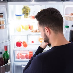 Mann der nachdenklich in einen Kühlschrank schaut