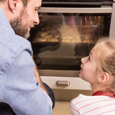 Vater und Tochter schauen in den Backofen