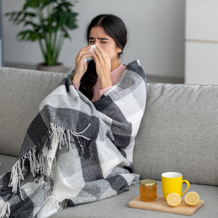 Junge Frau mit Schnupfen auf dem Sofa