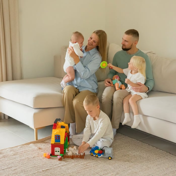 Familie geniesst Spielzeit mit Kindern und Spielzeug auf einem gemütlichen Sofa drinnen.