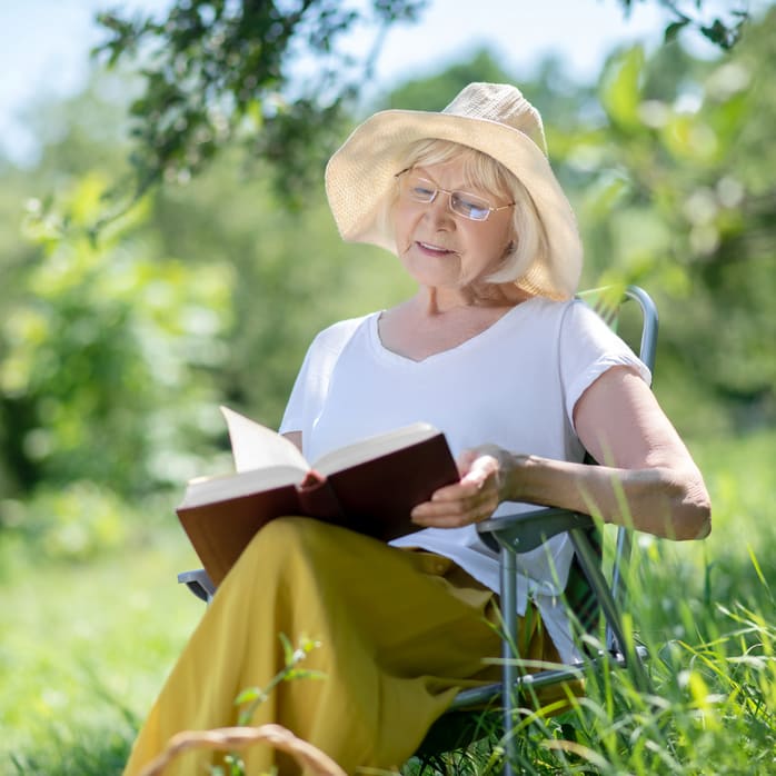 Eine ältere Frau liest ein Buch an der frischen Luft